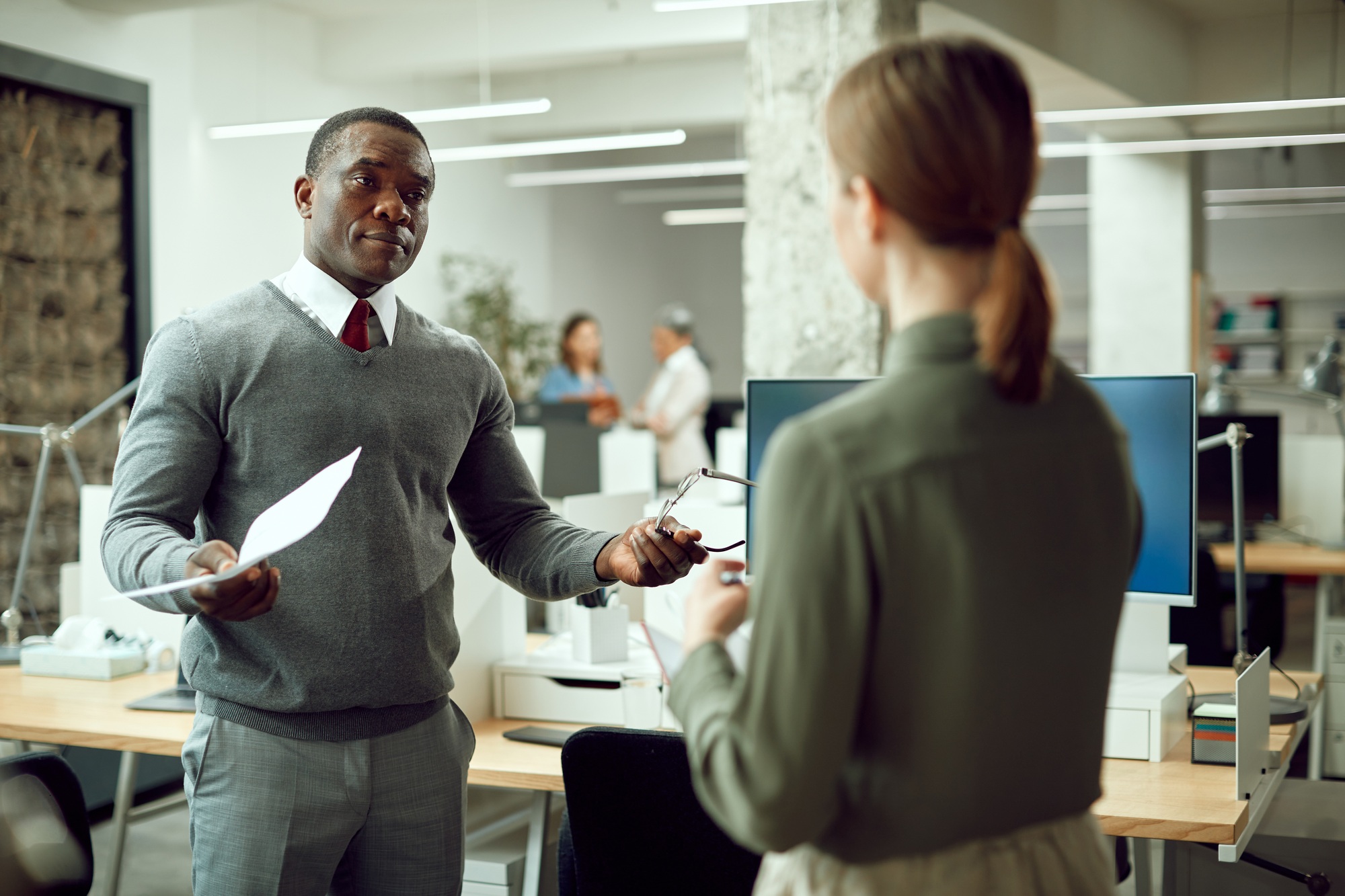 African American business mentor communicating with female coworker in the office.